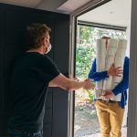 Man delivering huge pile of toilet rolls to customer in mask
