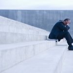 Frustrated Hispanic businessman sitting on steps