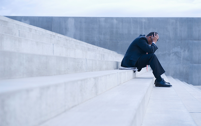 Frustrated Hispanic businessman sitting on steps